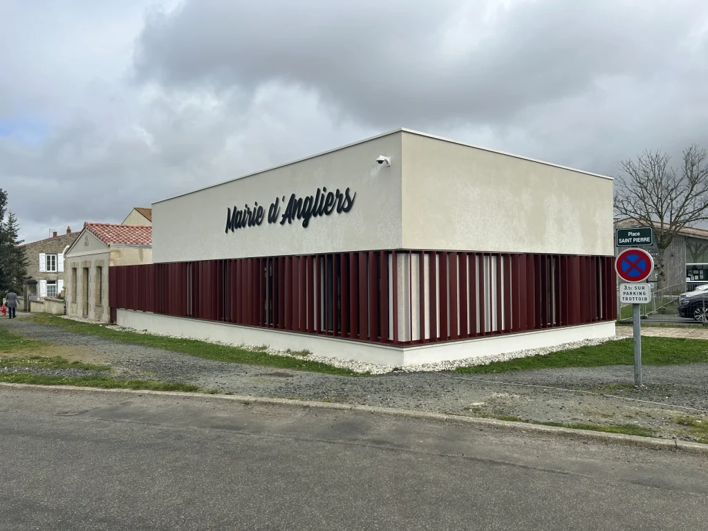 La mairie d’Angliers, place Saint-Pierre : un bâtiment blanc aux lames de bois rouge.